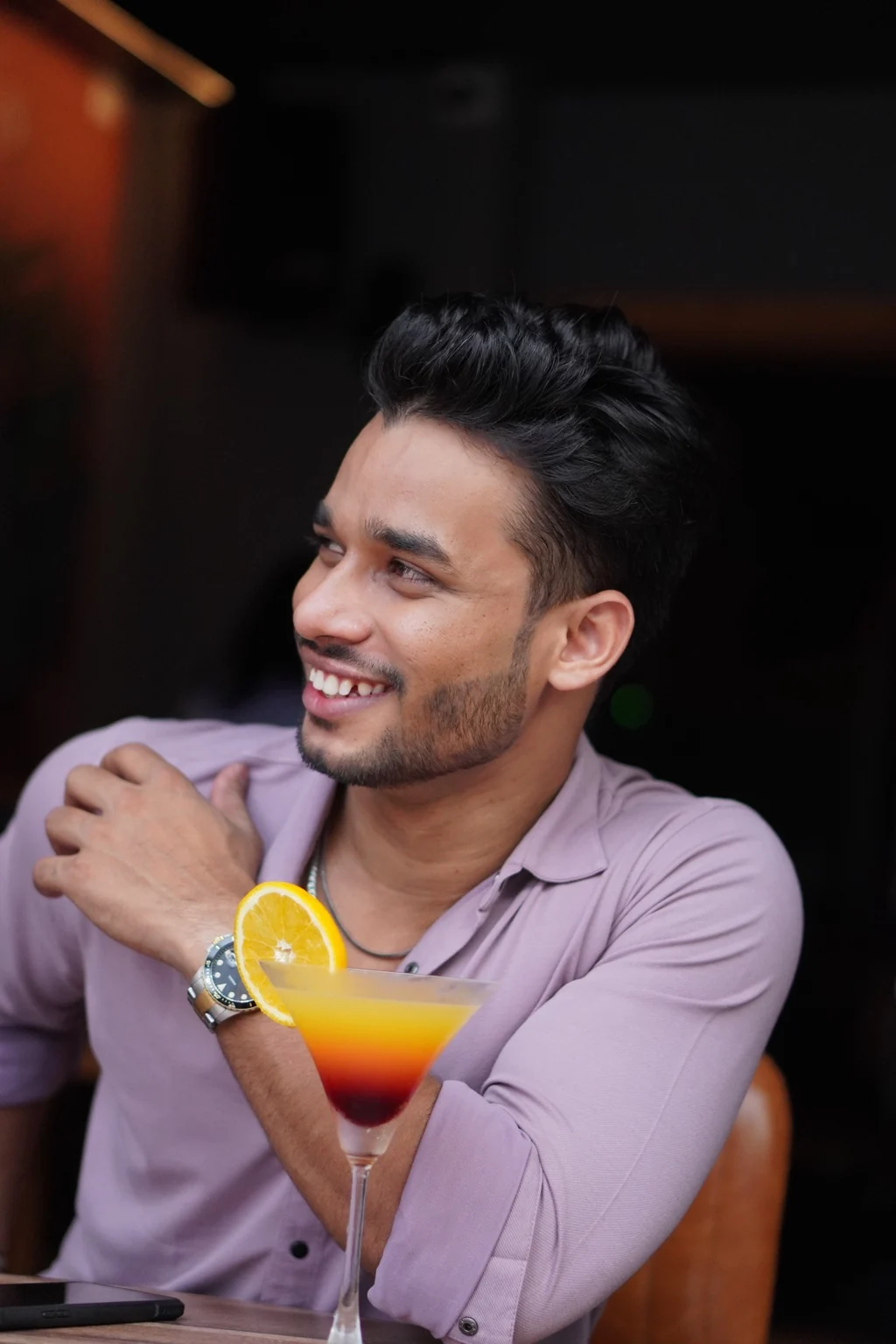 Rahul Manhar smiling beside a colourful cocktail
